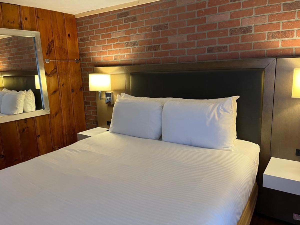 King bed against a brick accent wall with knotty pine panelling