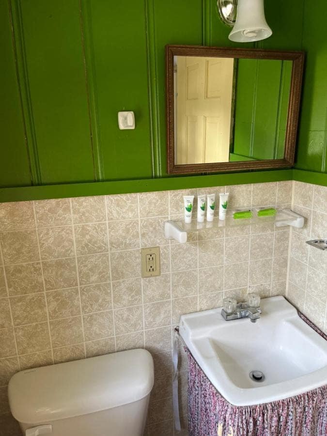 Cabin bathroom with green wainscoting and a tiled surround