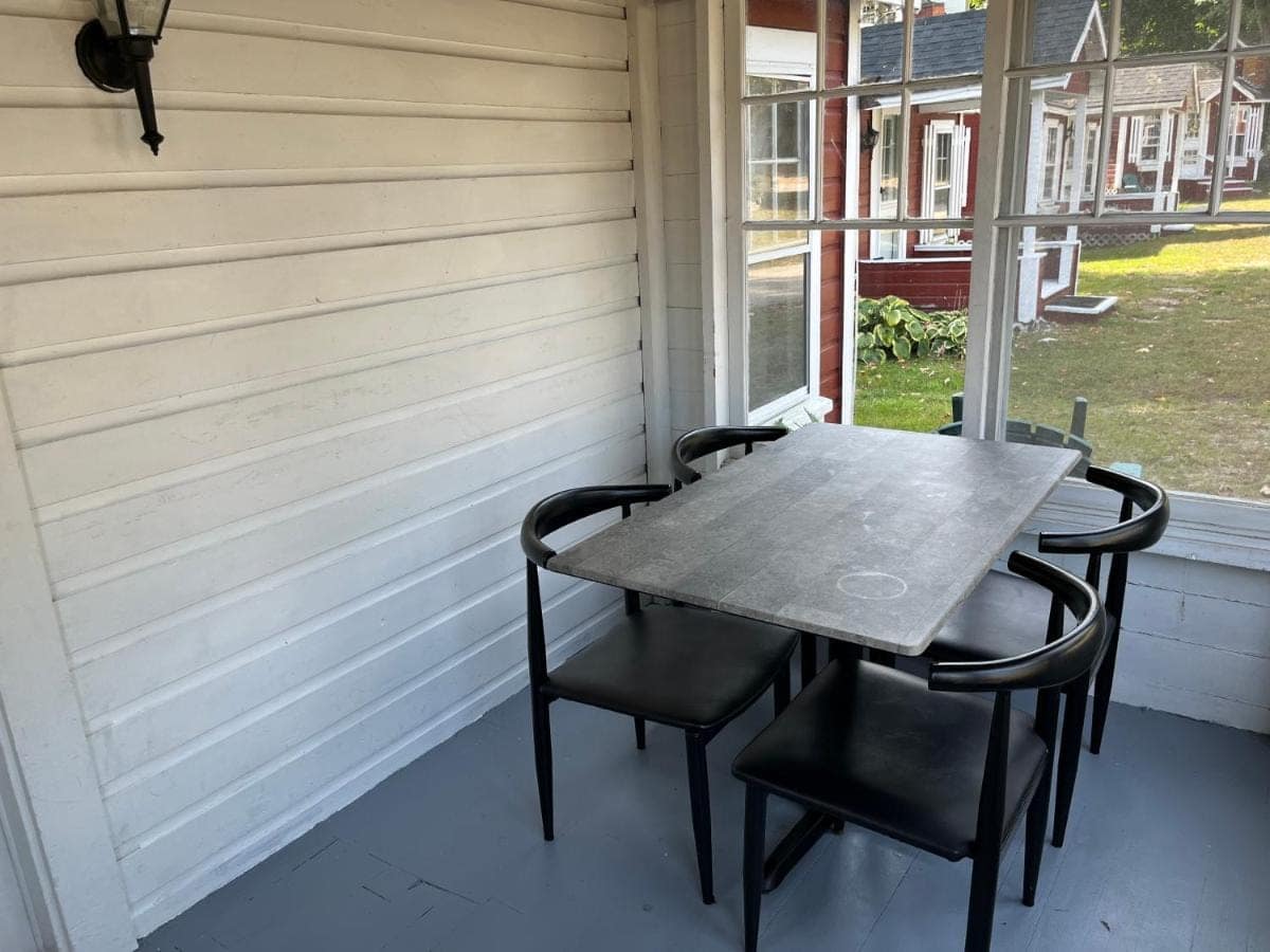Screened porch with a dining table looking out across the cabins