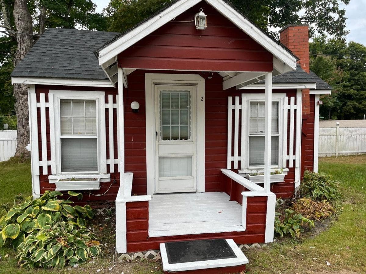 Cabin two in red clapboard with hostas along the porch