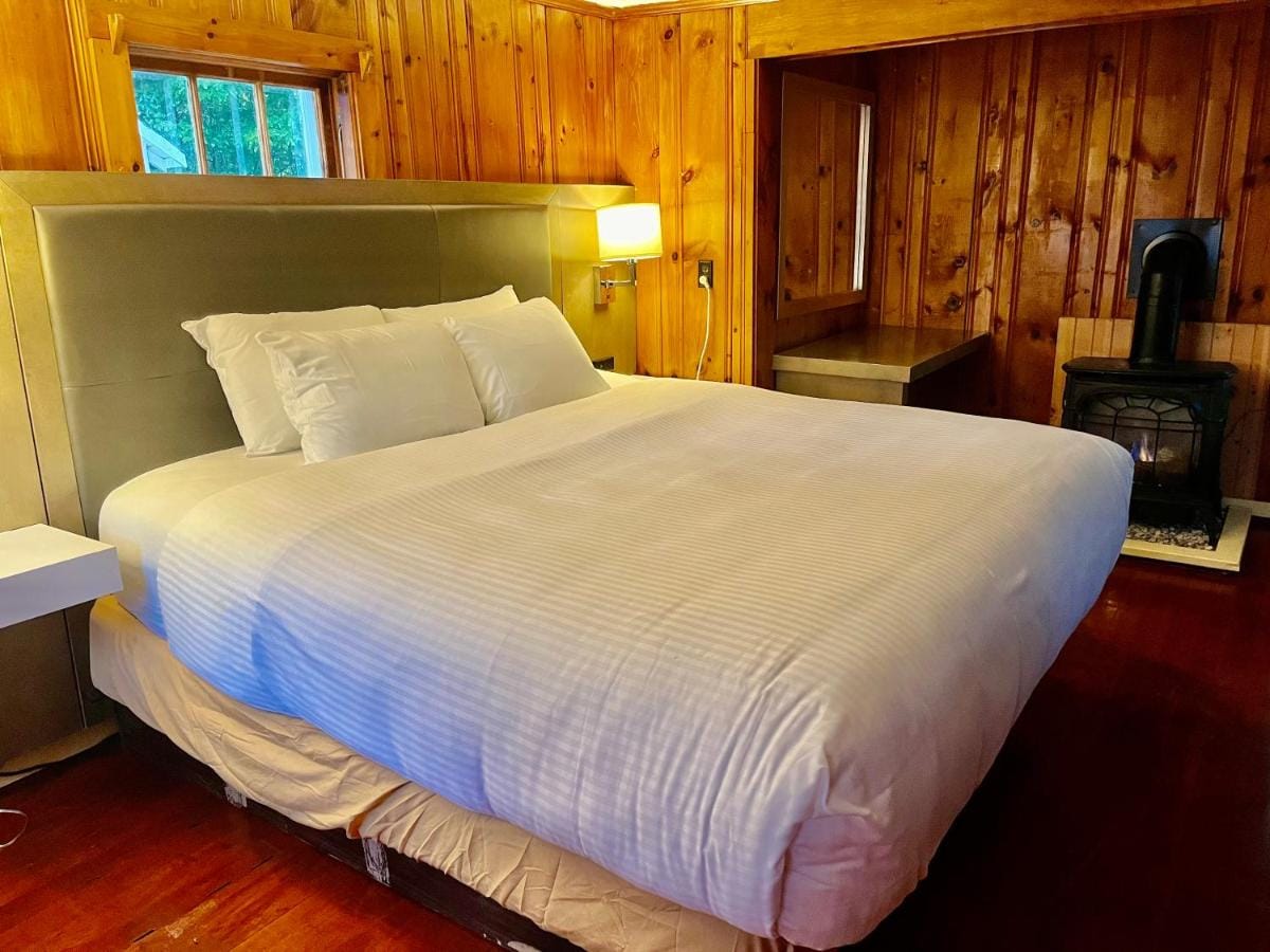 Bed beside a gas stove in a pine-panelled cabin